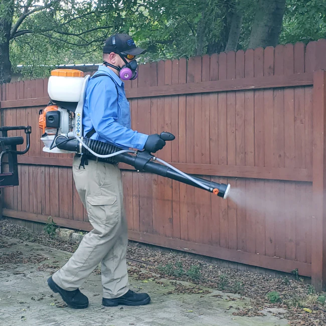 an exterminator applying insecticide during pest control service irving tx
